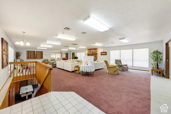 Expansive interior with carpeted flooring, multiple windows, a wood-finish staircase, and built-in overhead lighting