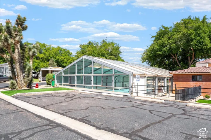 Enclosed swimming pool with a transparent roof, adjacent to a paved parking area
