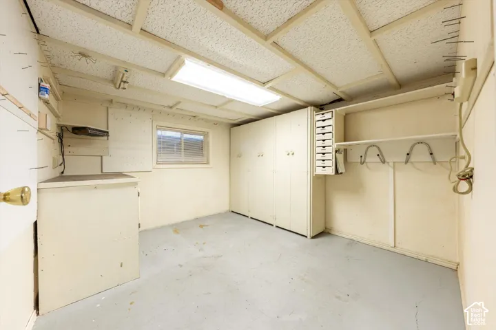 Window-equipped utility space featuring built-in cabinetry, shelving, and a drop-ceiling