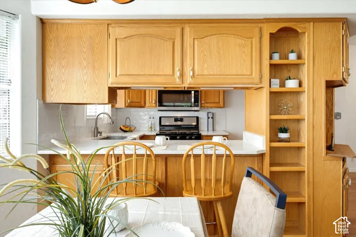 Kitchen featuring wood cabinetry, white countertops, tile backsplash, and built-in shelving