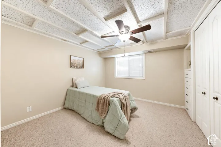 Carpeted room featuring a ceiling fan, recessed window, and built-in closet with drawers