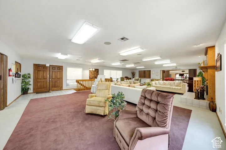 Expansive interior featuring twin wood-paneled entry doors, wood railing, recessed lighting, and a prominent built-in fireplace with a hearth