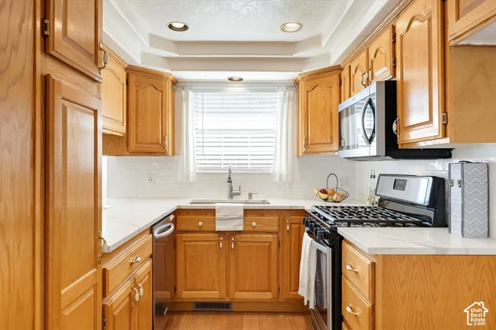 Kitchen featuring wood cabinetry, white countertops, subway tile backsplash, stainless steel appliances, and recessed lighting
