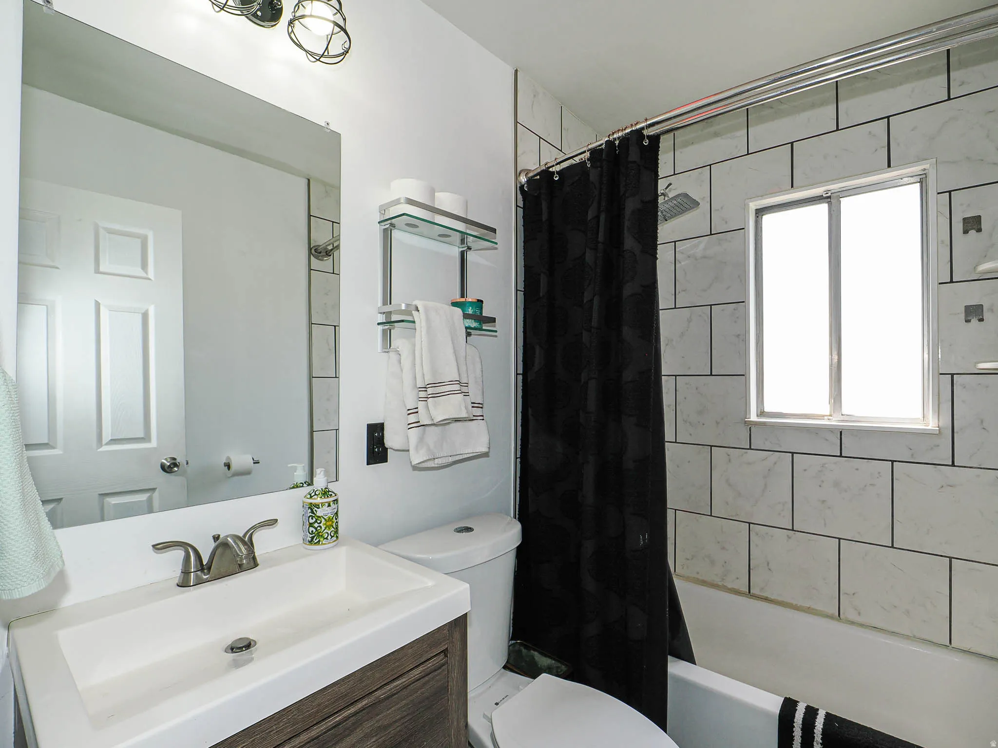 Bathroom featuring a wood-finish vanity with a sink with brushed nickel faucet, nice tile work and overhead vanity lighting