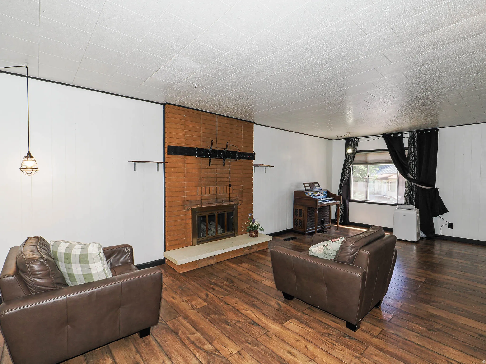 Living area featuring wood-finish flooring and a brick fireplace with a light-colored hearth