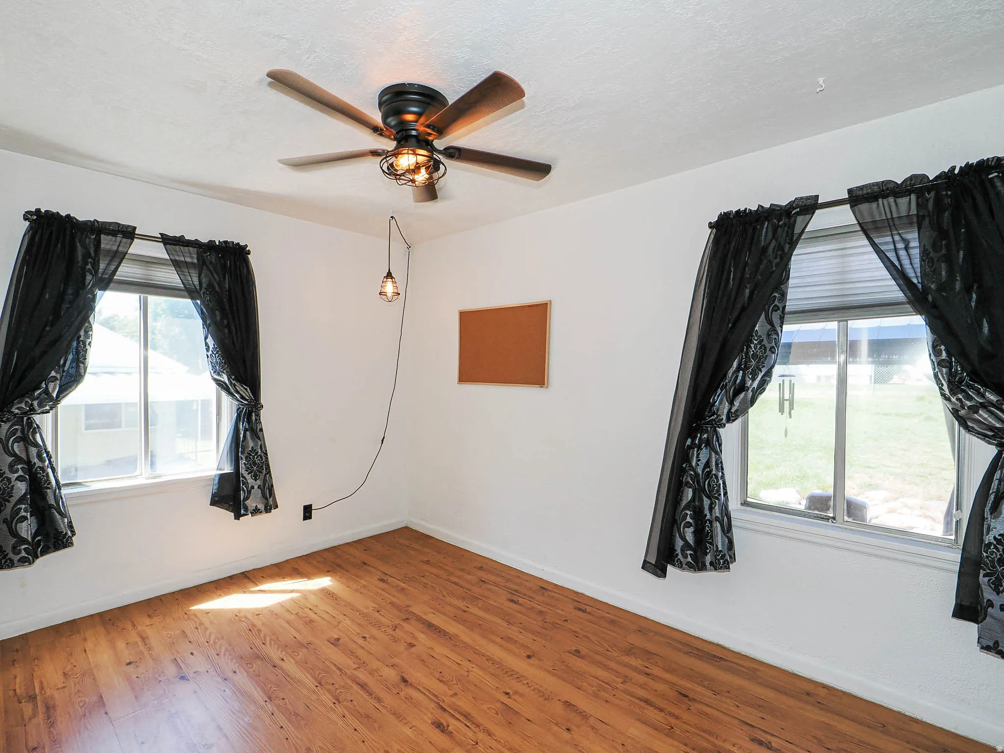 Room featuring wood-finish flooring and a ceiling fan with integrated lighting