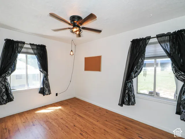 Room featuring wood-finish flooring and a ceiling fan with integrated lighting