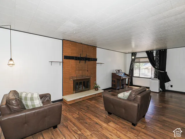 Living area featuring wood-finish flooring and a brick fireplace with a light-colored hearth