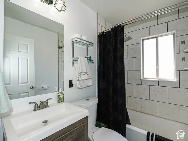 Bathroom featuring a wood-finish vanity with a sink with brushed nickel faucet, nice tile work and overhead vanity lighting