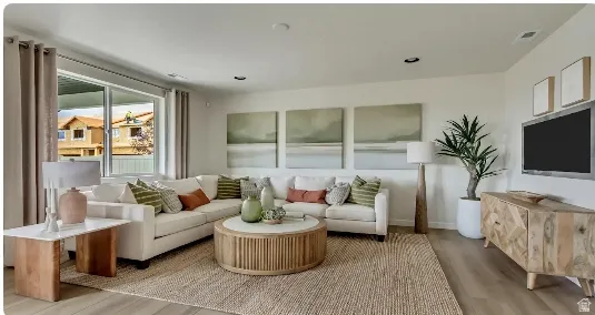 Spacious living area featuring light wood-finish flooring, recessed lighting, and a large sliding glass door. Home is TO BE BUILT. Pictures are of a similar model.