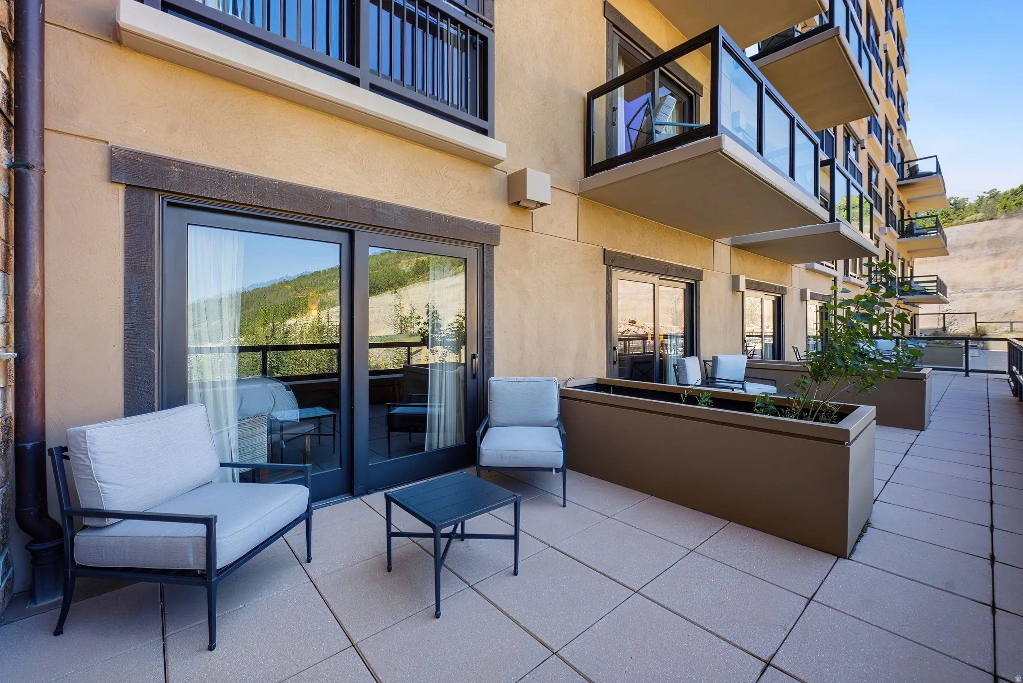 Spacious outdoor patio featuring large-format paver tiles, a stucco exterior, and sliding glass doors
