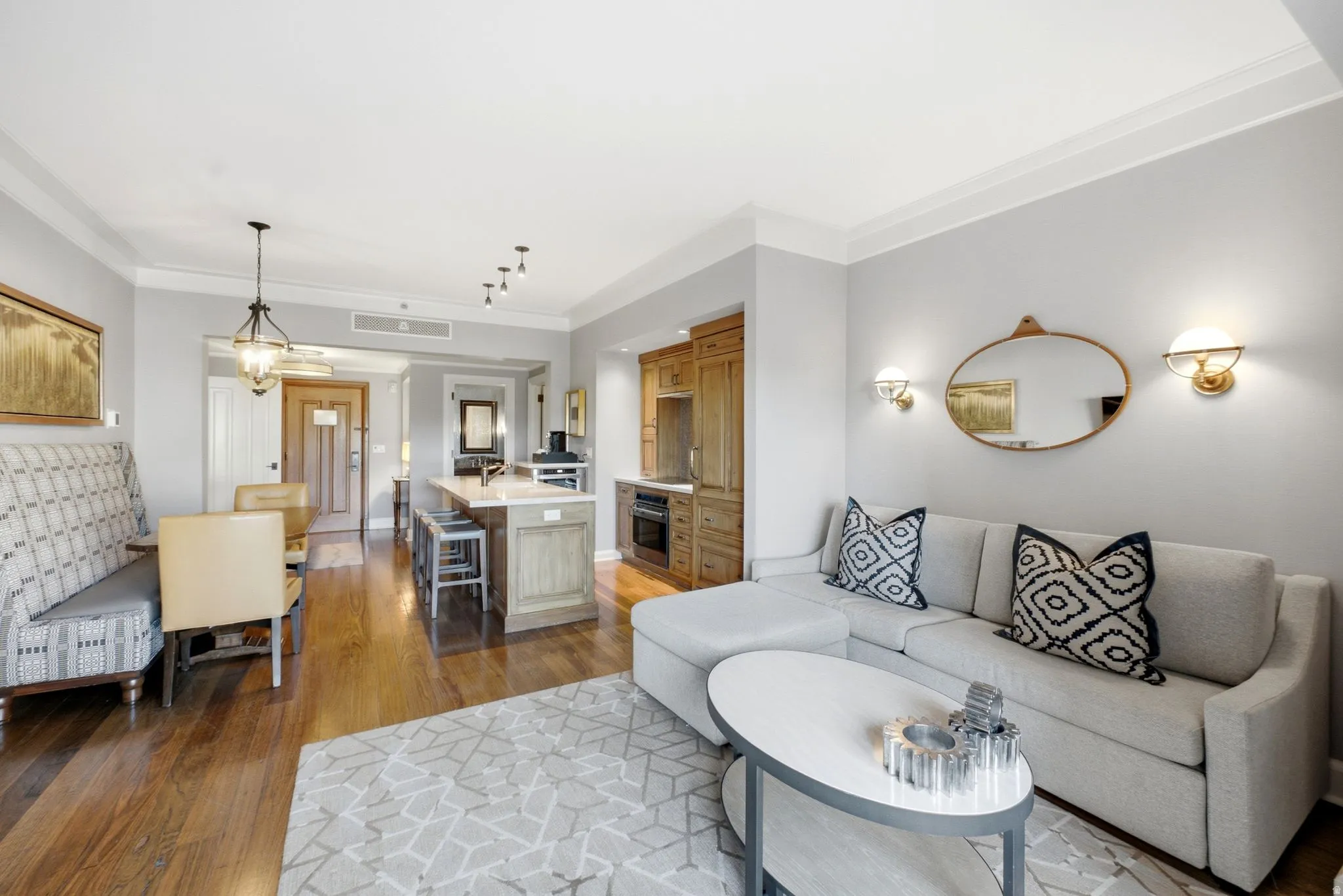 Hardwood flooring throughout the main living areas, crown molding, kitchen island with seating, built-in cabinetry, and integrated appliances