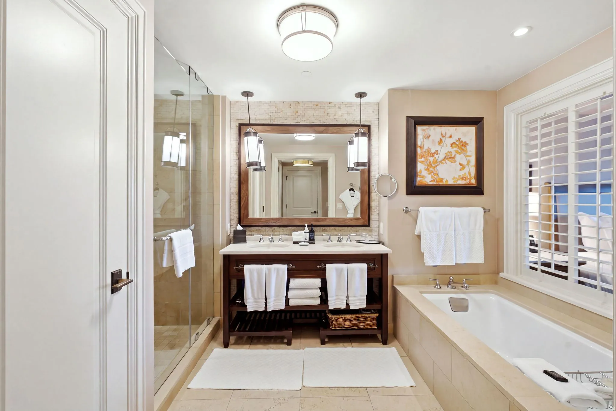 Full bathroom featuring a single vanity with stone countertop, frameless glass shower enclosure, built-in bathtub, and window with plantation shutters