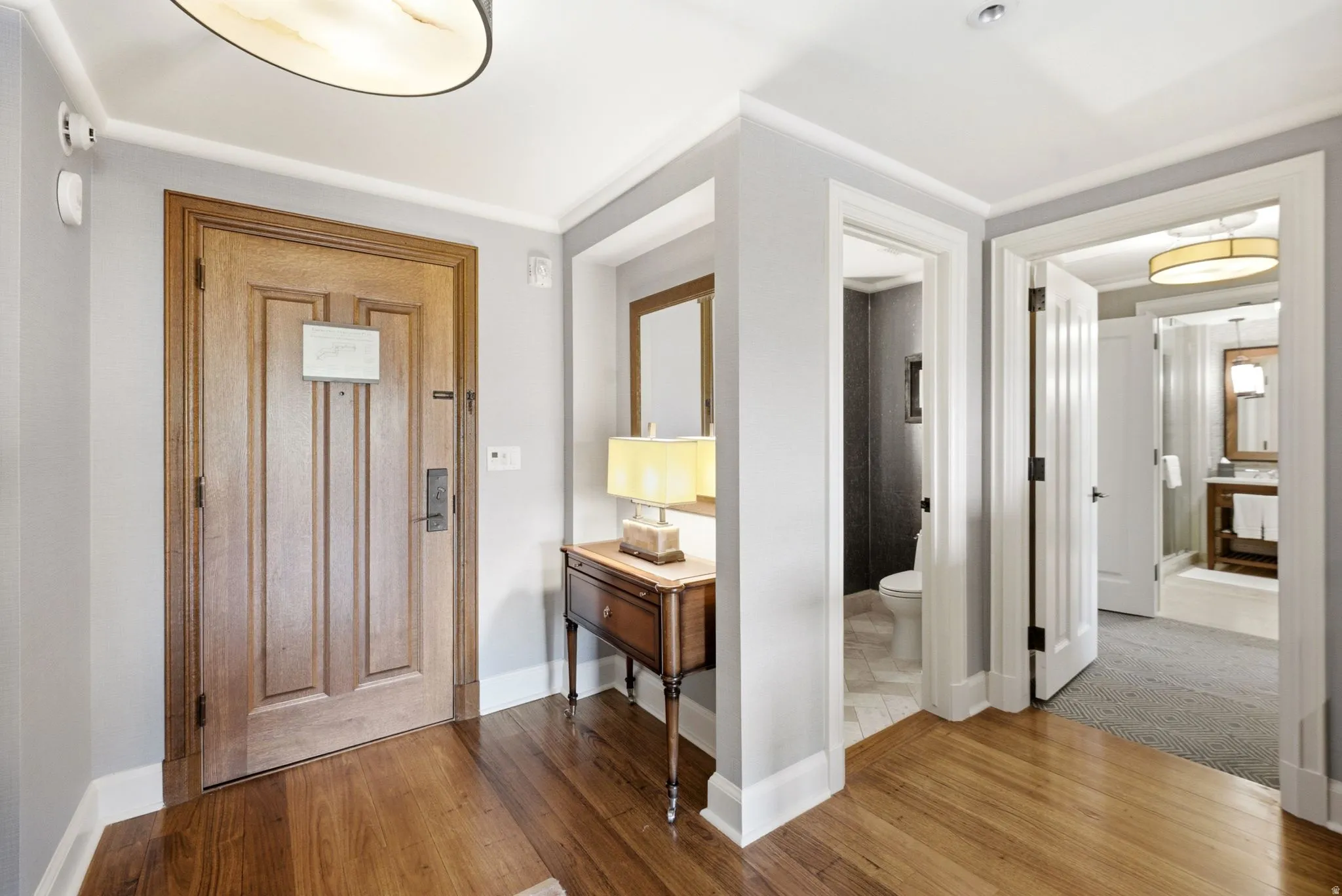 Hardwood flooring entry with crown molding, panel doors, and recessed lighting