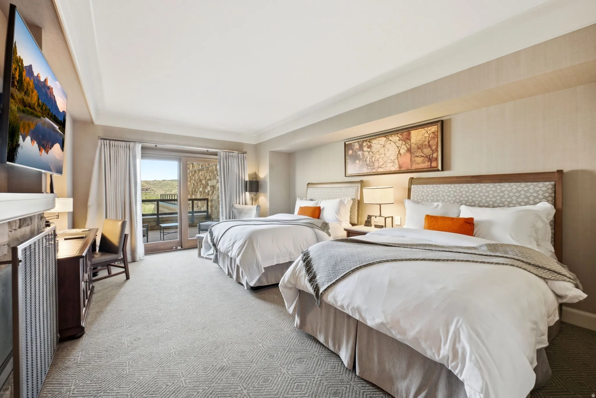 Spacious room featuring patterned carpeting, twin beds with upholstered headboards, and a glass-paned door opening to an exterior balcony