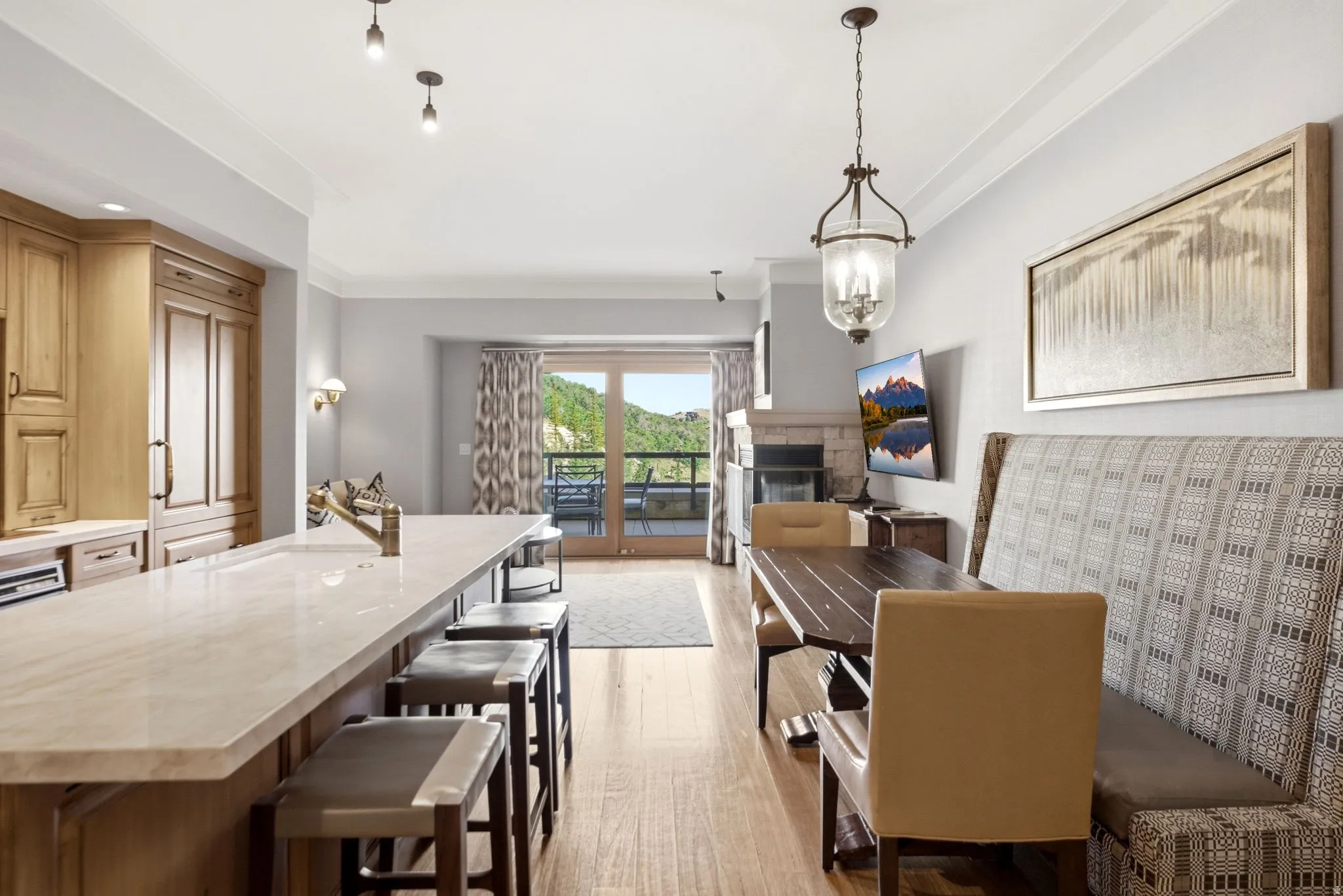 Open-concept living space featuring hardwood flooring, a stone fireplace, and a large kitchen island with counter seating