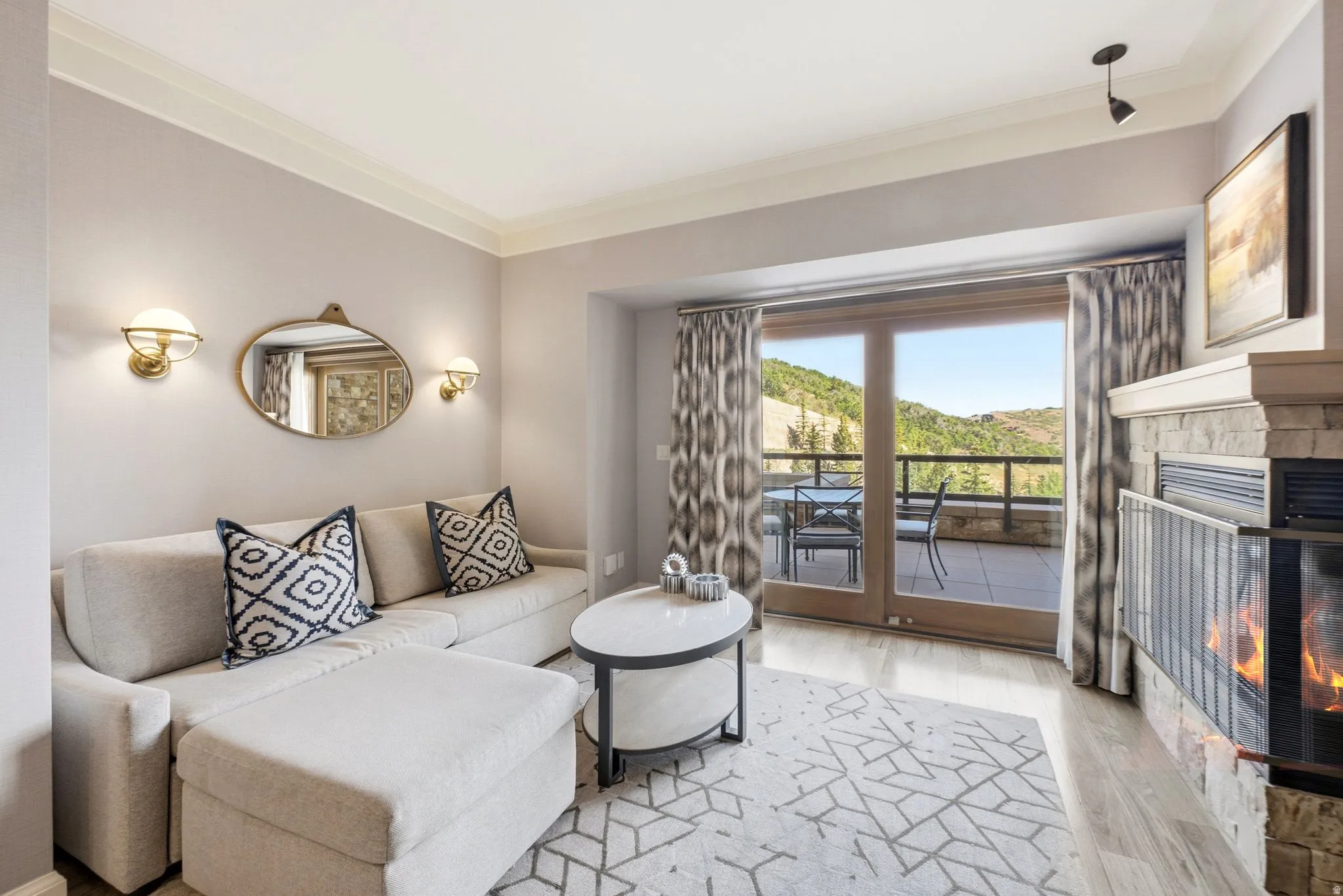 Living area featuring a stone-clad fireplace, direct access to an outdoor patio with mountain scenery, and wood-finish flooring
