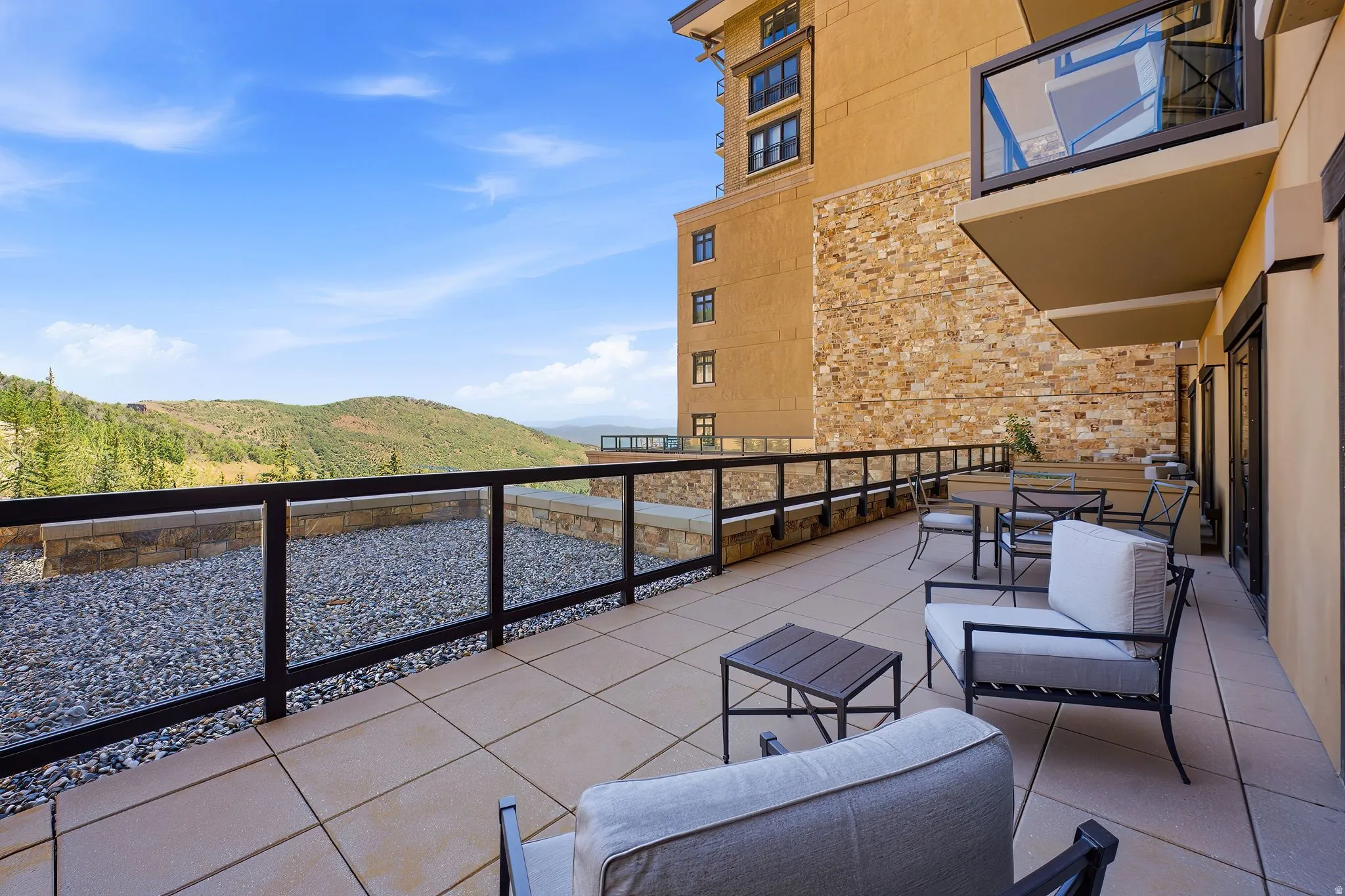 Spacious outdoor terrace with large format patio pavers and glass panel railing