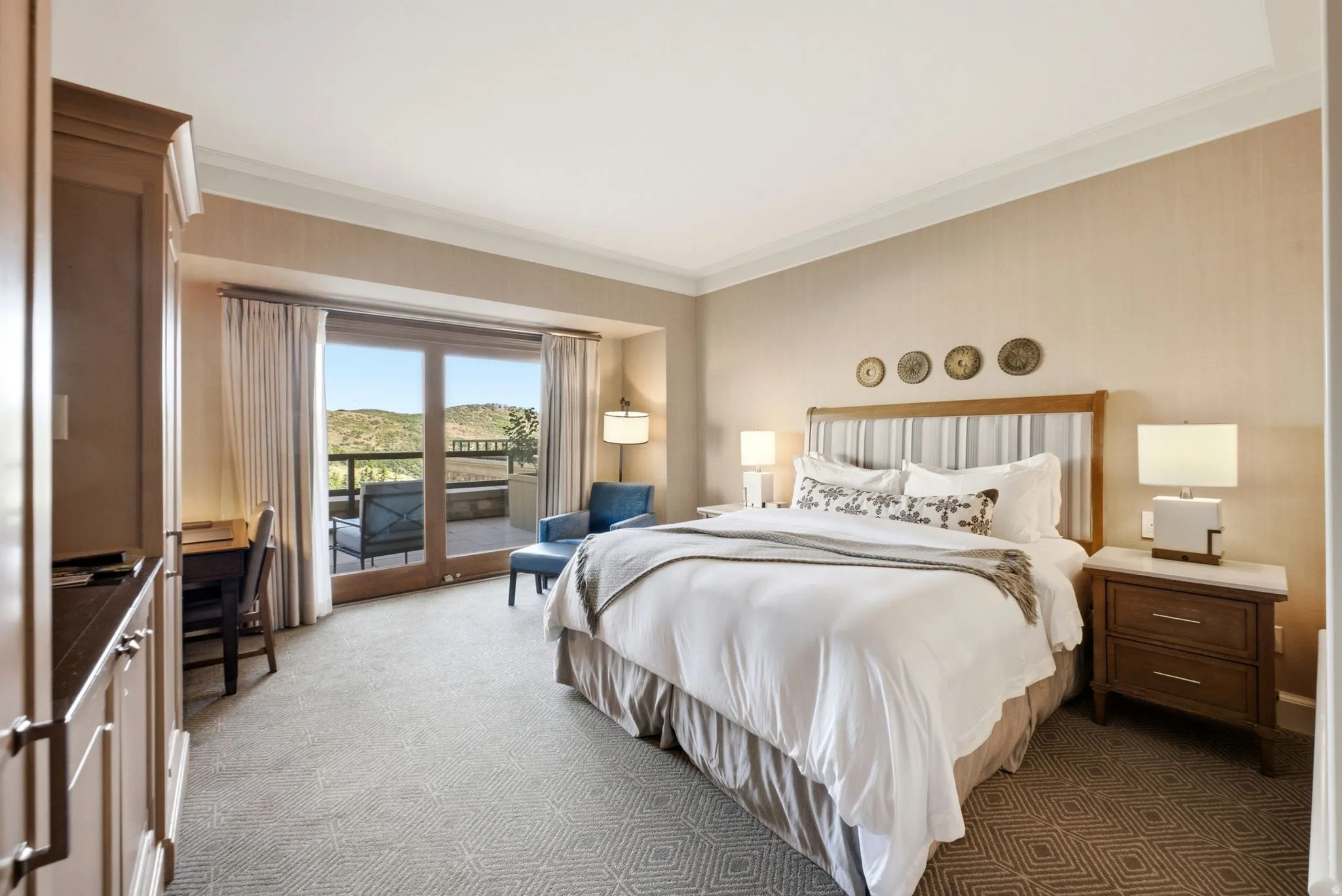 Spacious room with a private balcony, wood-finish sliding glass doors, built-in cabinetry, patterned carpet, and crown molding