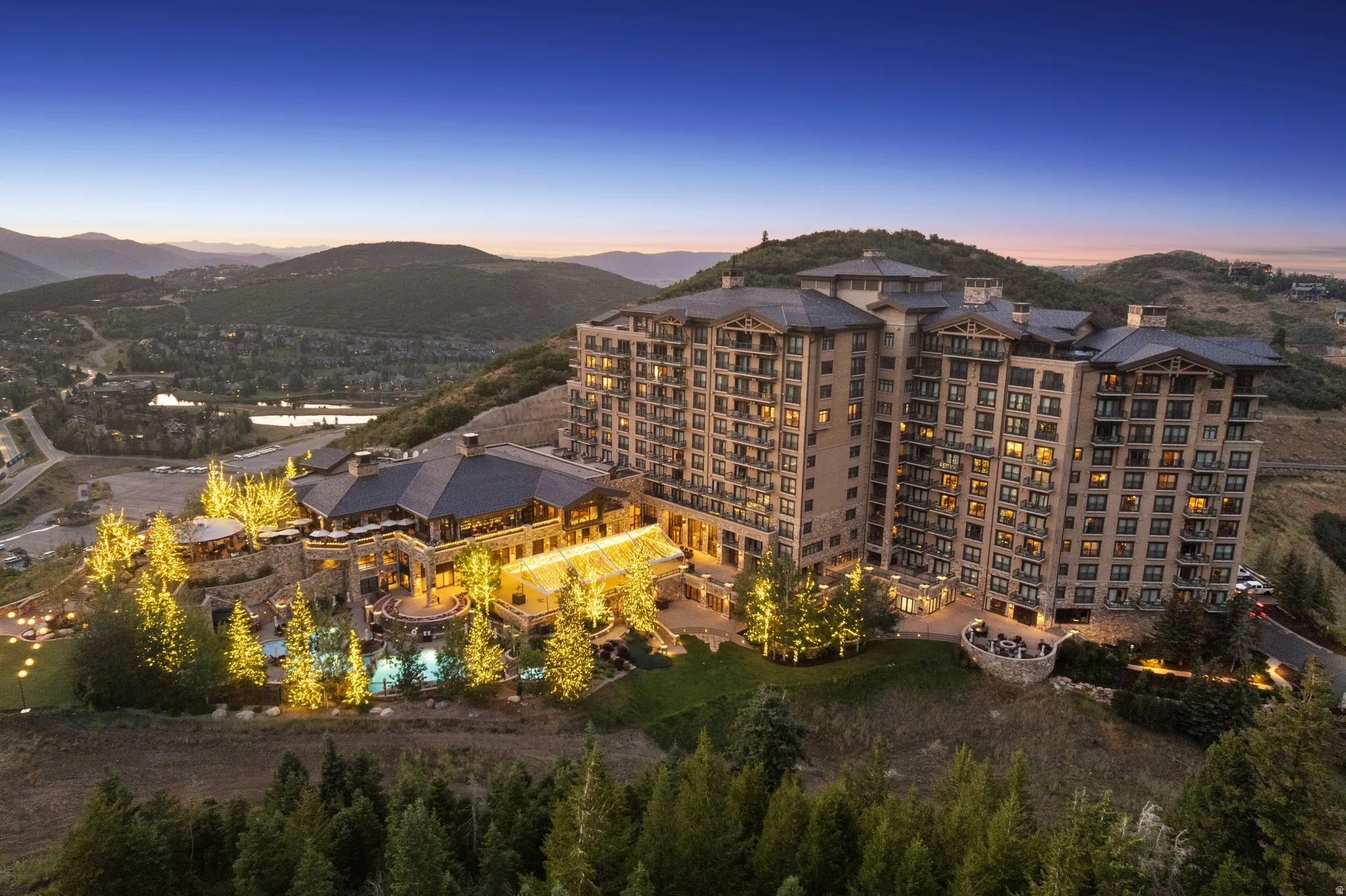 Multi-story building featuring numerous balconies and a large, multi-level recreational area with multiple pools