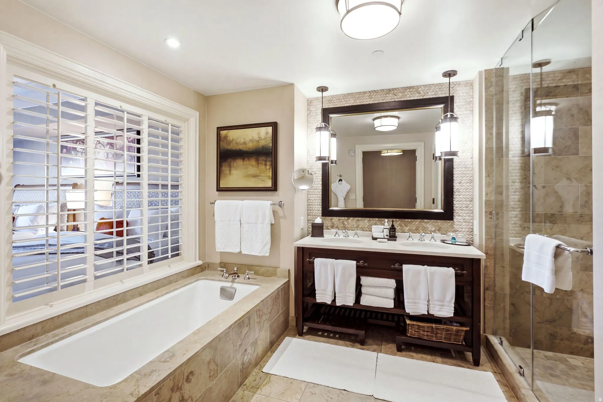 Spacious bathroom featuring a built-in soaking tub with stone surround, a dual vanity with undermount sinks, and a glass-enclosed shower with stone tile