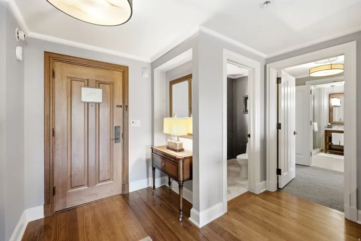 Hardwood flooring entry with crown molding, panel doors, and recessed lighting