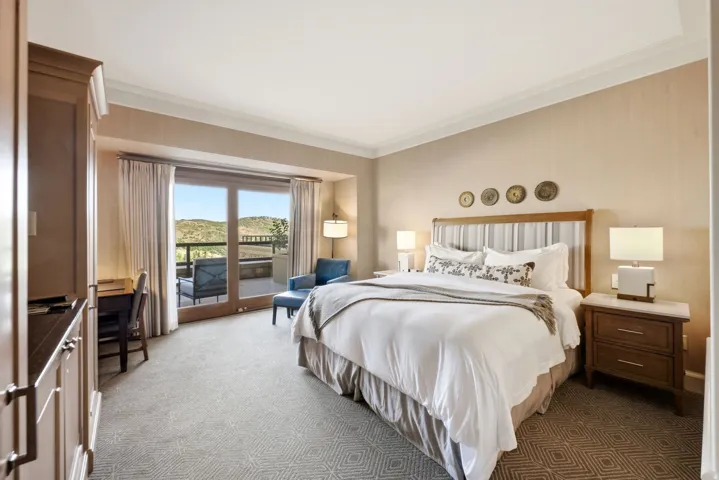 Spacious room with a private balcony, wood-finish sliding glass doors, built-in cabinetry, patterned carpet, and crown molding