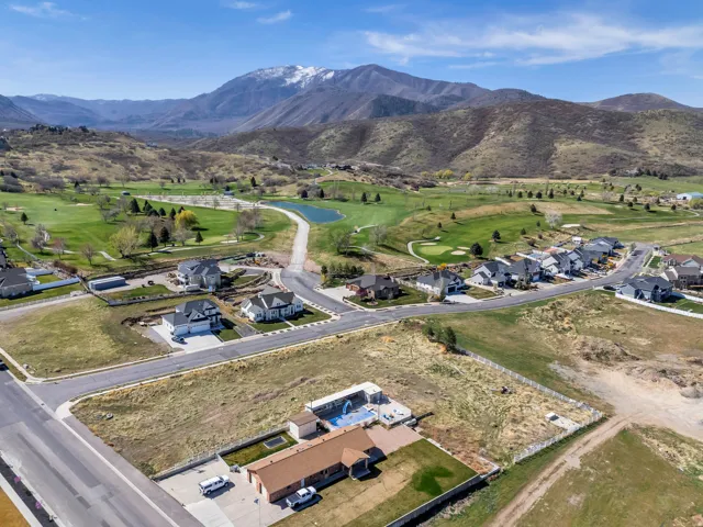 Expansive aerial perspective showcasing a residential area with a golf course backdrop and distant snow-capped mountains