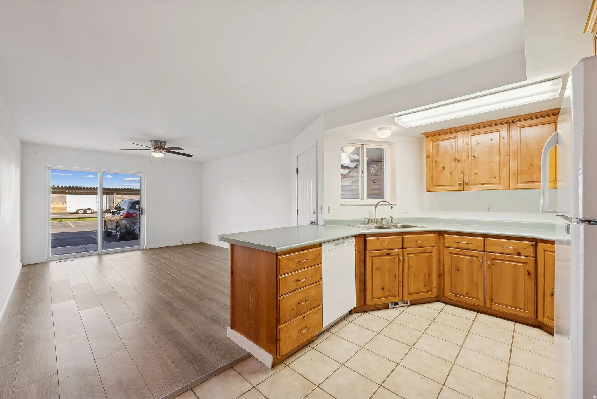 Open-concept kitchen and living area featuring wood-finish flooring, a ceiling fan, and sliding glass doors