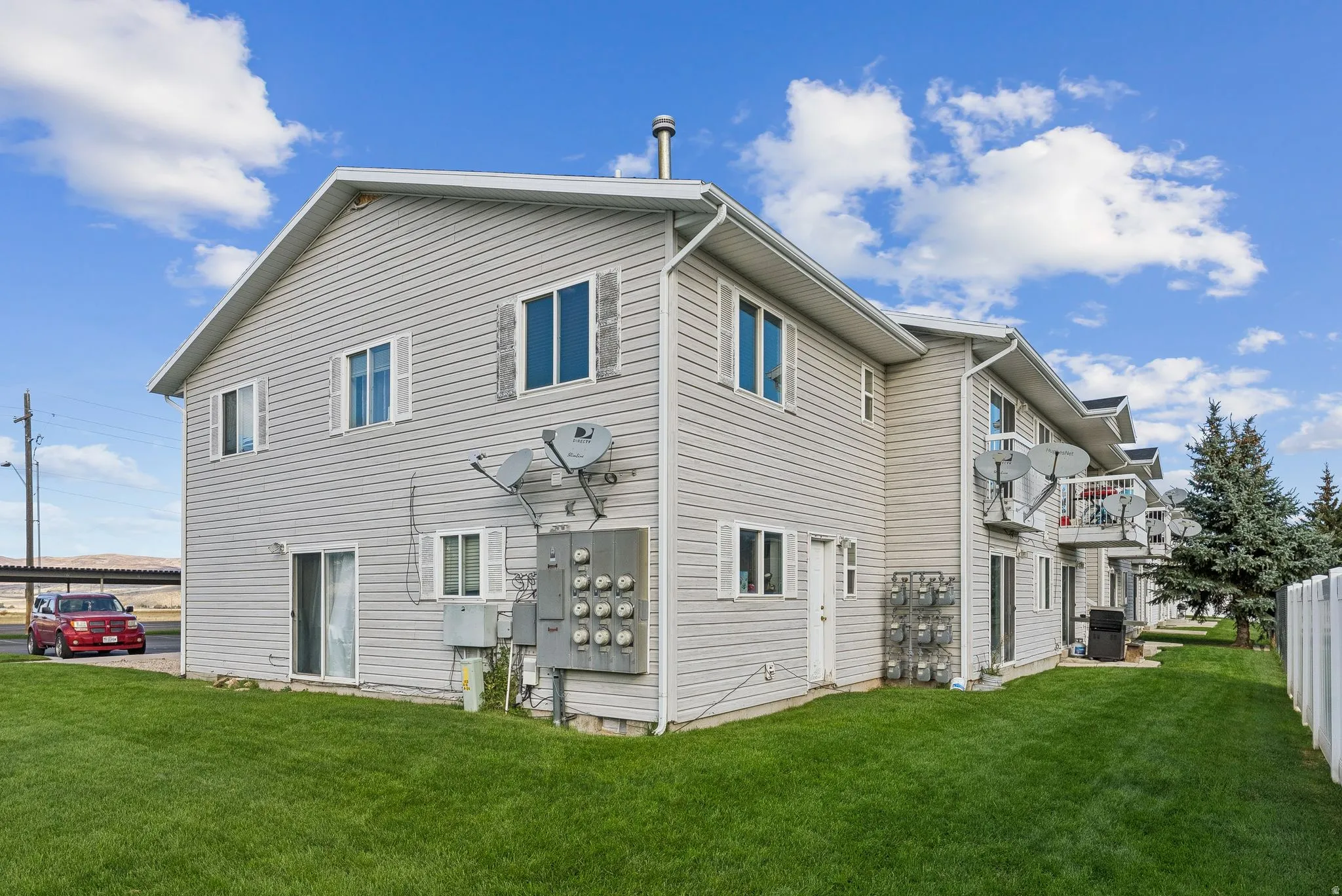 Multi-unit property with light gray horizontal siding, white trim, and a gabled roofline