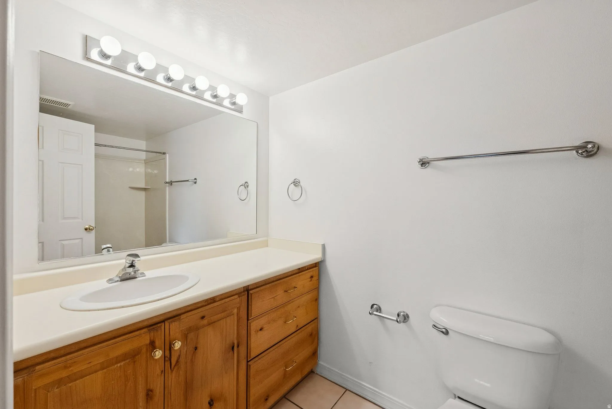 Bathroom featuring a single vanity with wood-finish cabinetry, a neutral countertop, and an oval sink
