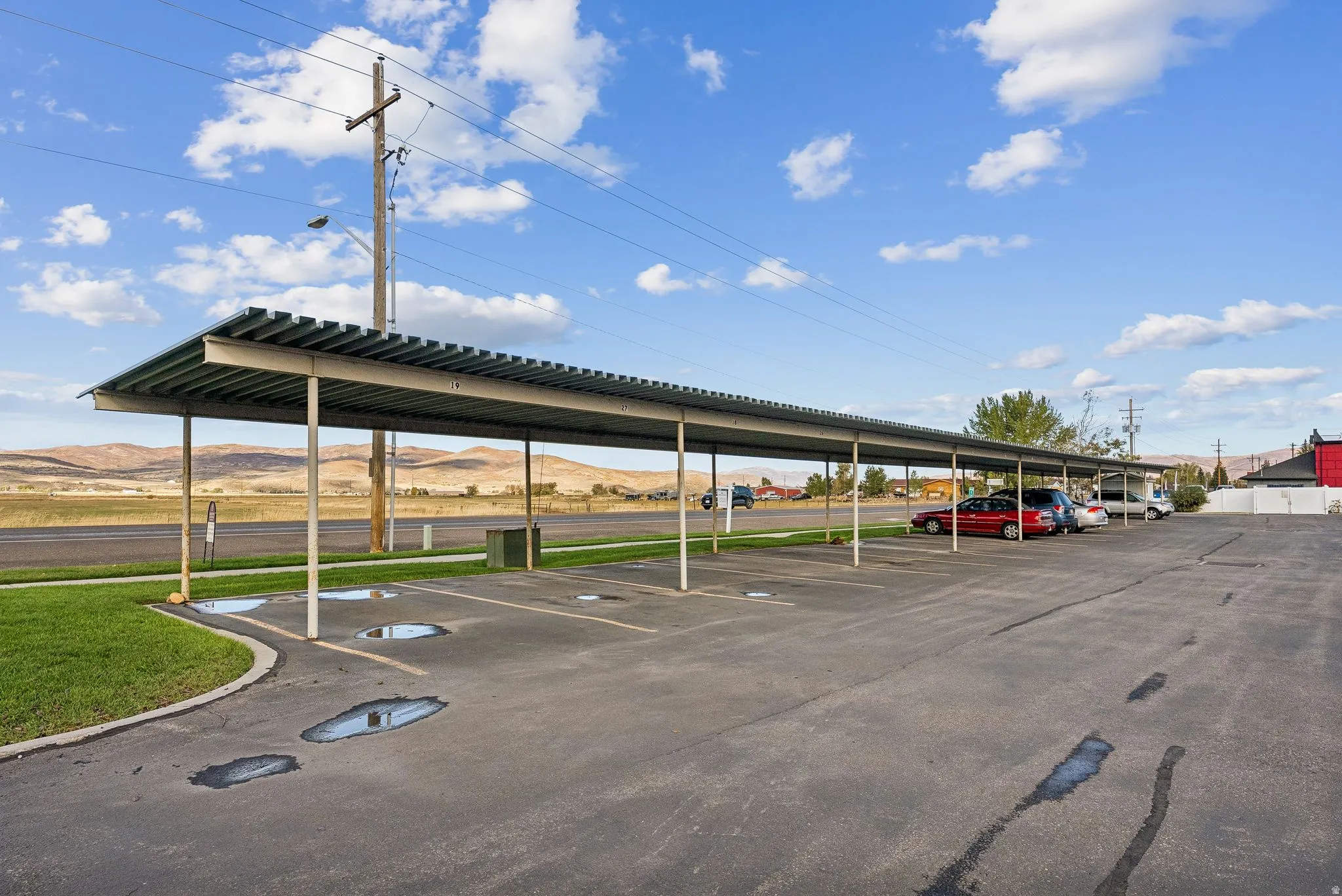 Covered parking structure featuring multiple bays, asphalt surfacing, and a defined grassy border