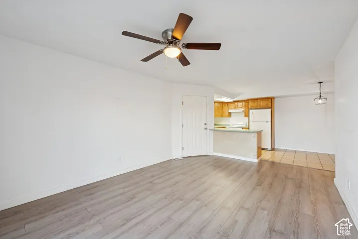 Spacious living area featuring wood-finish flooring, a ceiling fan, and white walls