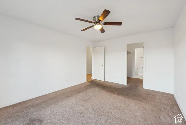 Carpeted room with white walls, featuring a ceiling fan with light fixture