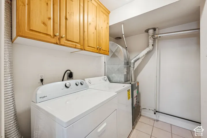 Laundry area featuring light wood-finish cabinetry, a white washer and dryer, and ceramic tile flooring