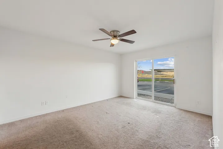 Spacious room featuring a ceiling fan with integrated lighting, white walls, and a sliding glass door providing external access