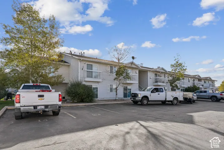 Multi-unit residential building featuring light-colored siding, multiple balconies with white railings, and sliding glass doors