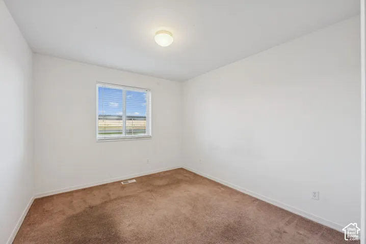 Carpeted room featuring a single window with horizontal blinds, a ceiling-mounted light fixture, and white painted walls