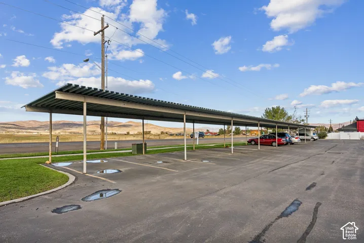 Covered parking structure featuring multiple bays, asphalt surfacing, and a defined grassy border