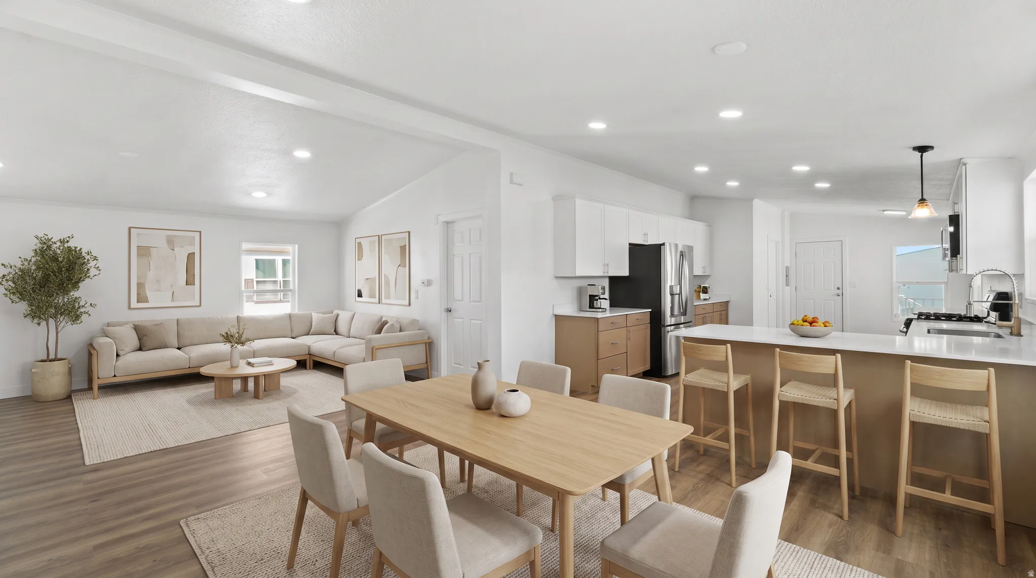 Open-concept living space with wood-finish flooring, vaulted ceilings, and recessed lighting