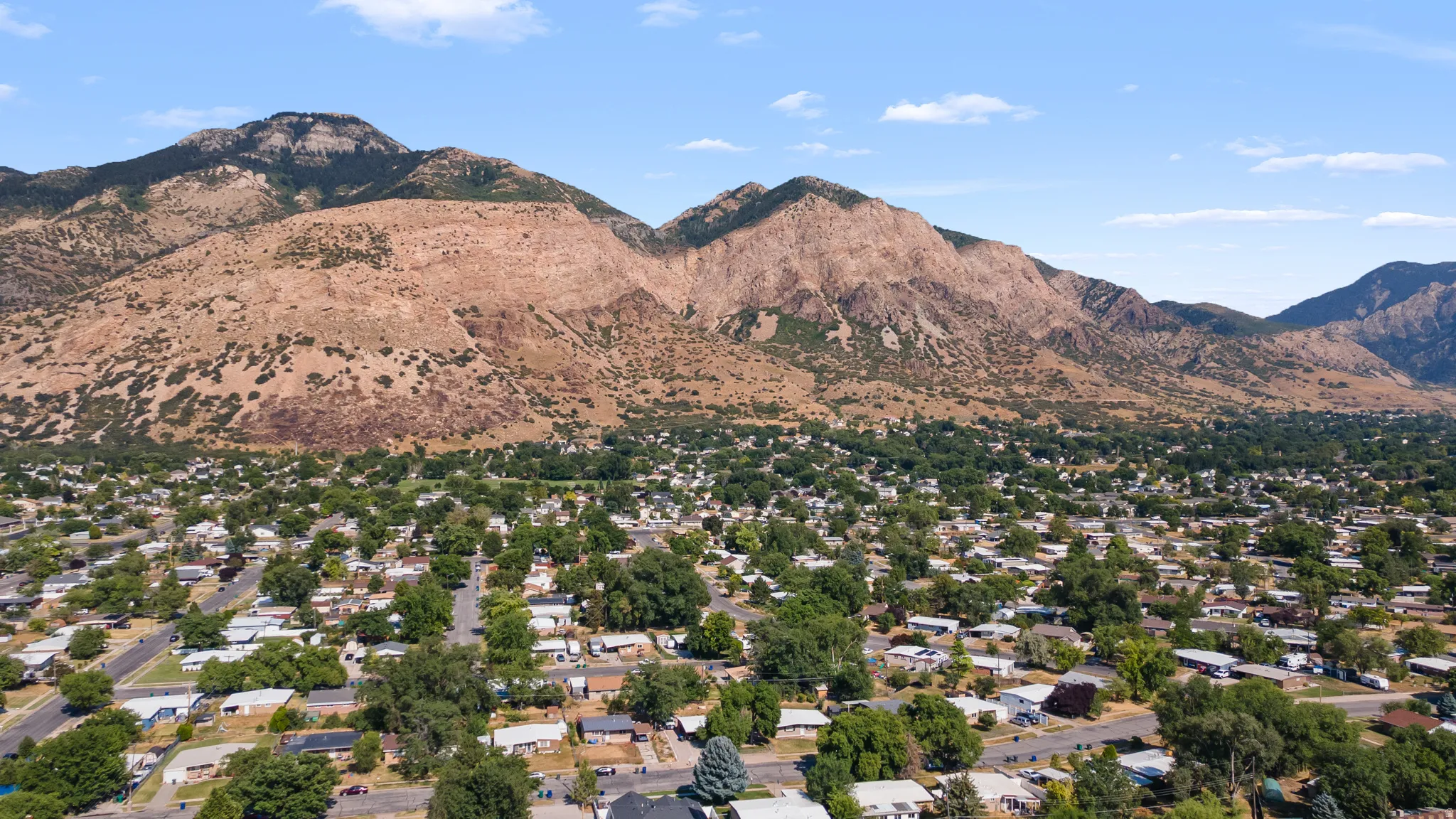 Neighborhood setting featuring mature trees and mountain backdrops