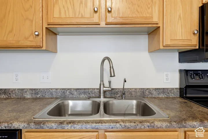 Dual basin stainless steel sink with a high-arc faucet, set within a speckled laminate countertop