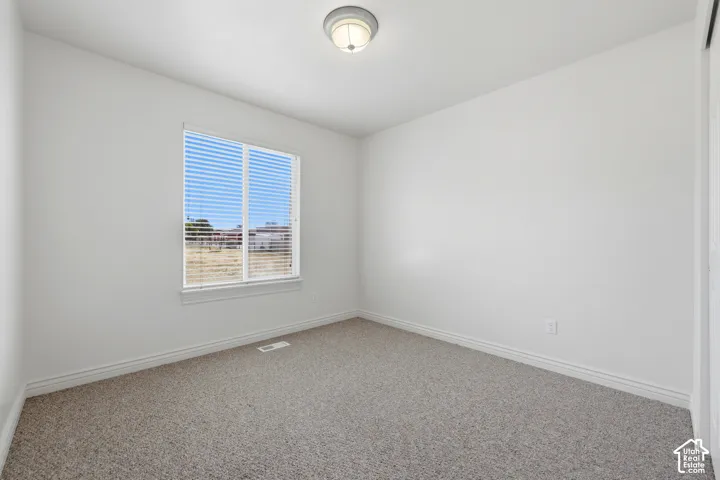 Carpeted room featuring a white ceiling, light-toned walls, and a window with horizontal blinds