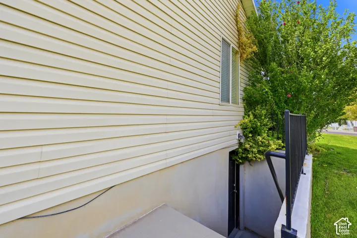 Exterior wall with horizontal siding, a window, and a separate basement entrance with a dark metal railing