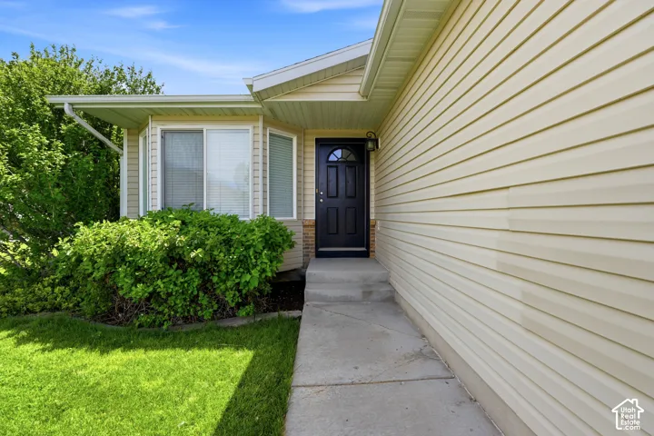 Exterior showcasing light-colored horizontal siding, a dark paneled entry door with an arched window, and a concrete walkway