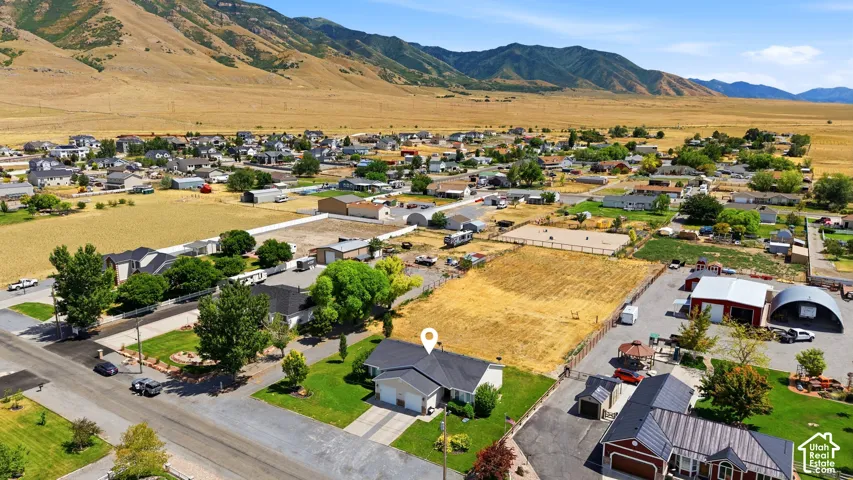 Aerial perspective showcasing the property's location within a residential area, bordered by open fields and distant mountains
