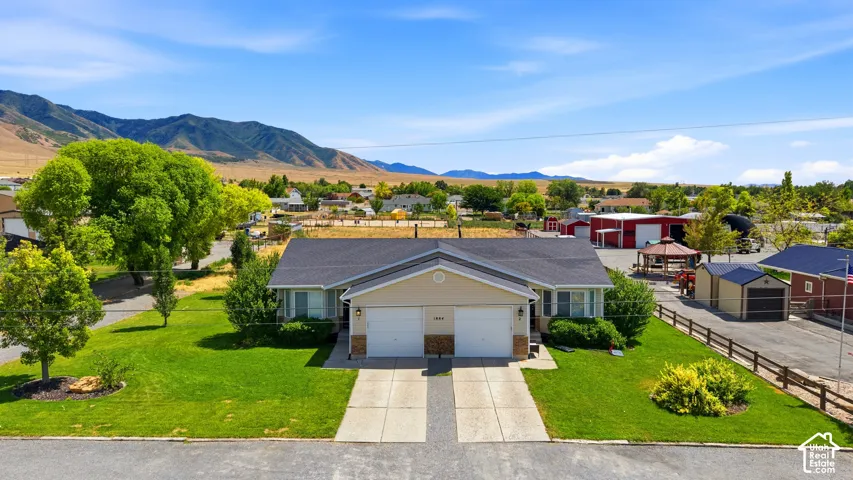 Ranch-style duplex featuring two single-car garages with individual driveways, stone accent siding, and established front landscaping