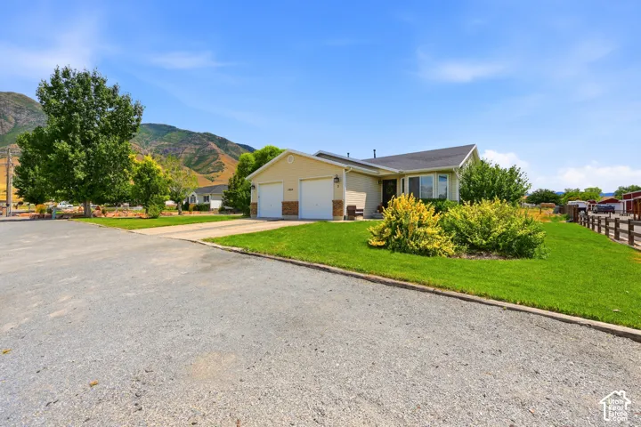 Ranch-style exterior with a two-car garage, manicured lawn, and mature landscaping