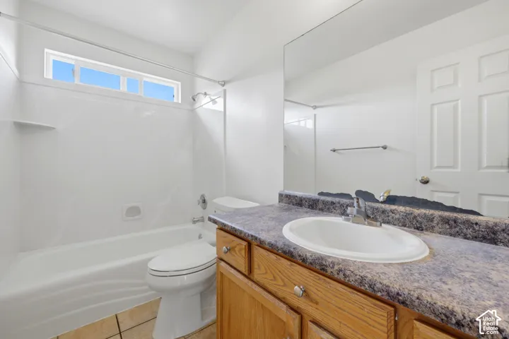 Bathroom featuring a bathtub/shower combination, a vanity with a laminate countertop, and a large wall-mounted mirror