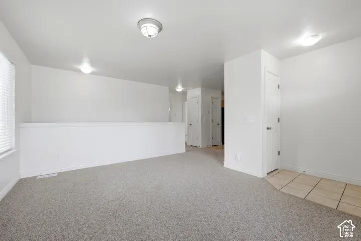 Carpeted interior space featuring neutral wall tones, white trim, and recessed lighting